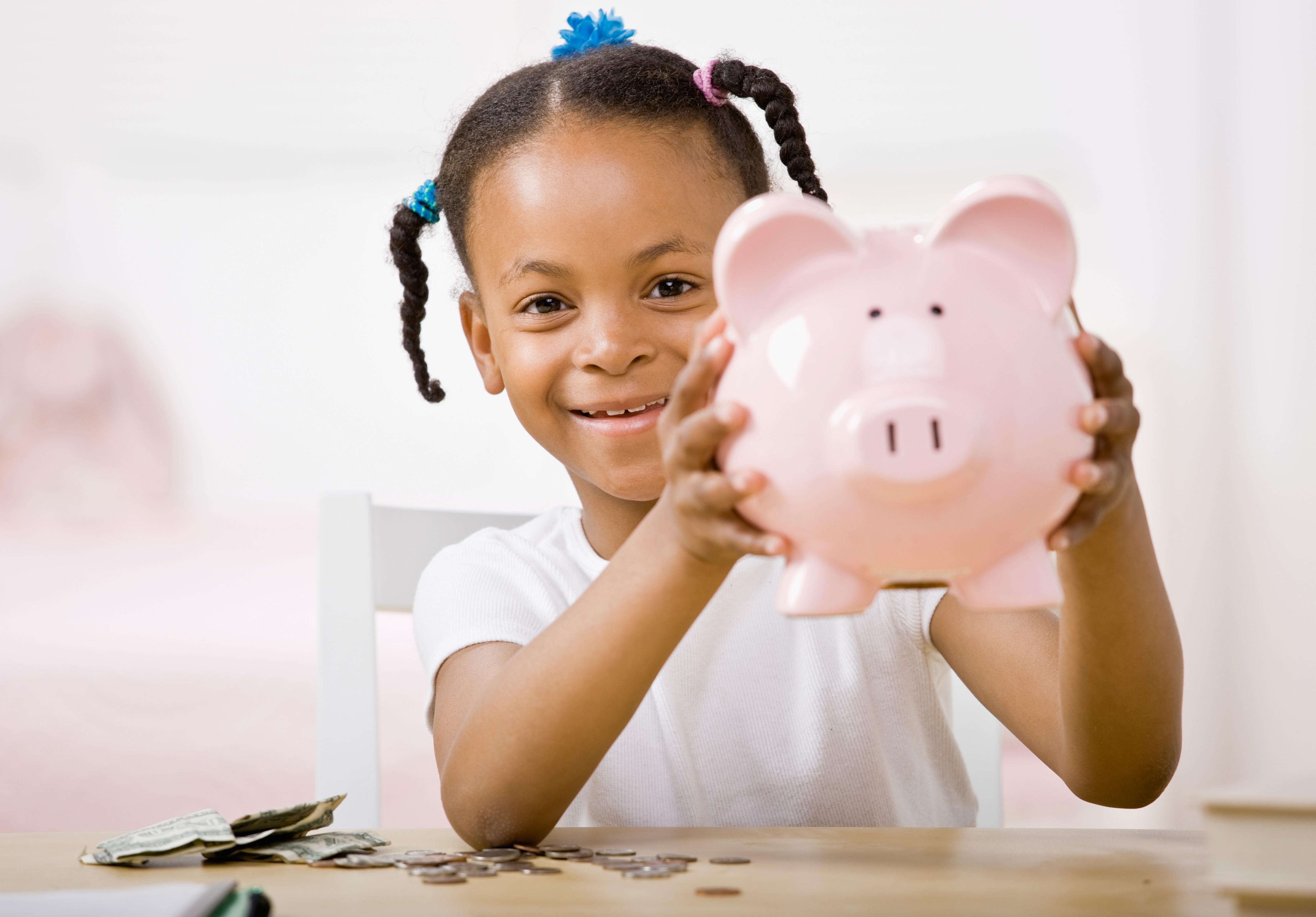 Little girl holding a piggy bank.