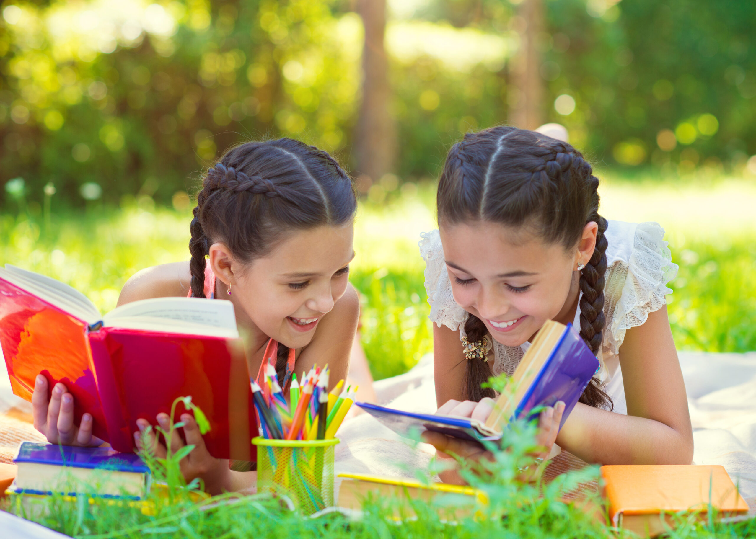 two young girls reading in the grass
