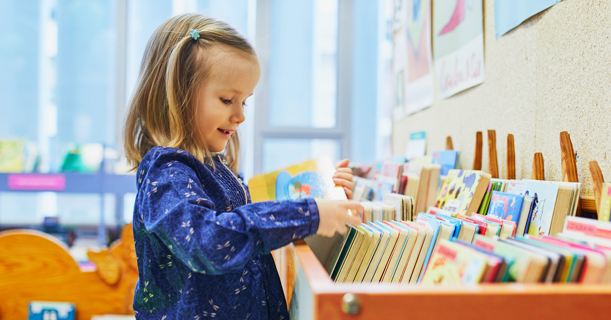 Little girl looking through books in a library