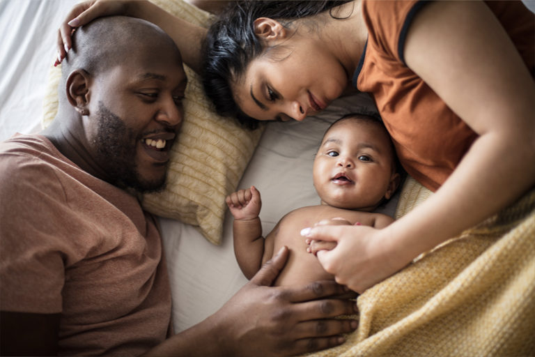 Mother father and infant baby on a bed