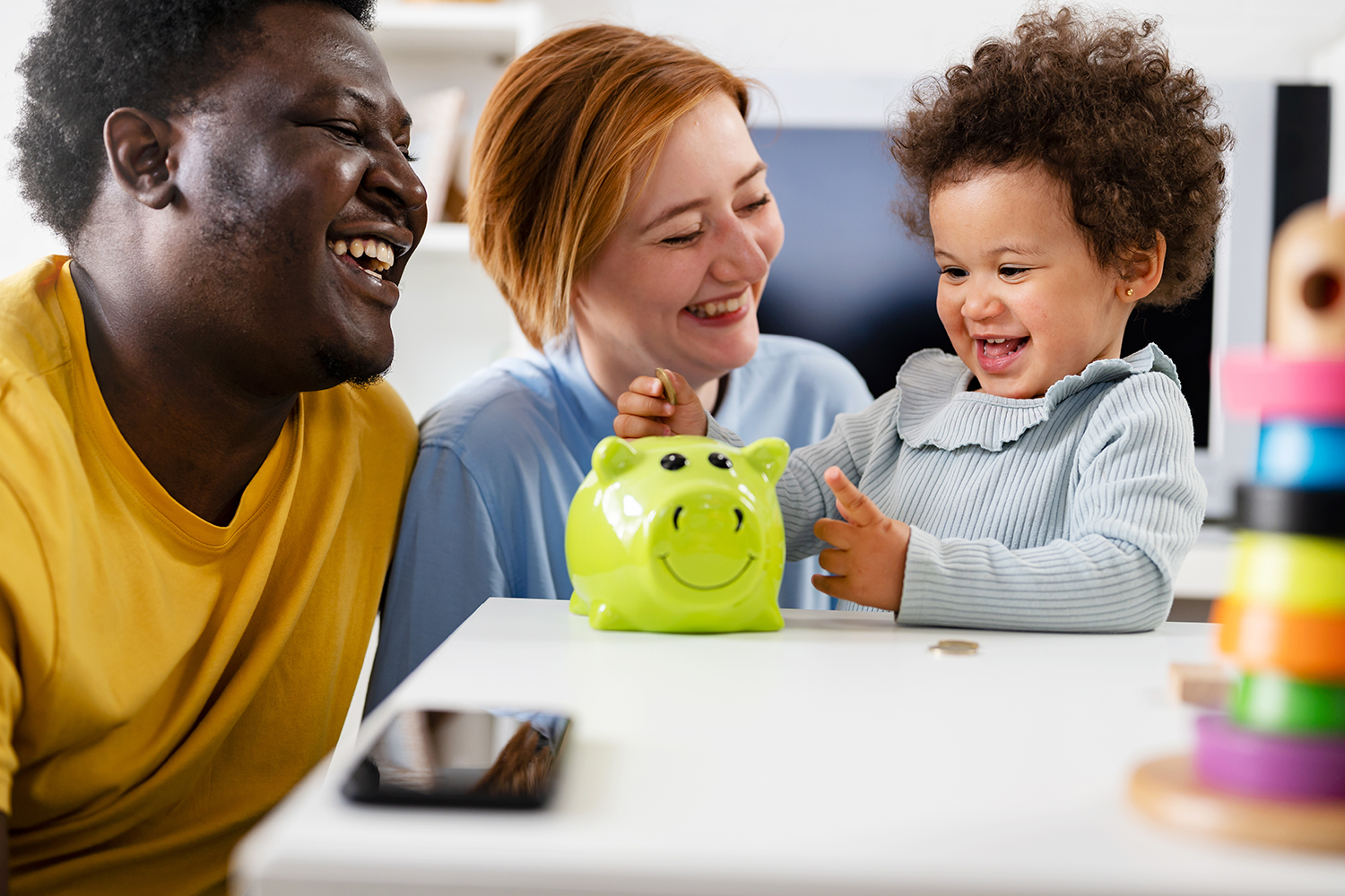 Young happy family adding money to a piggybank.