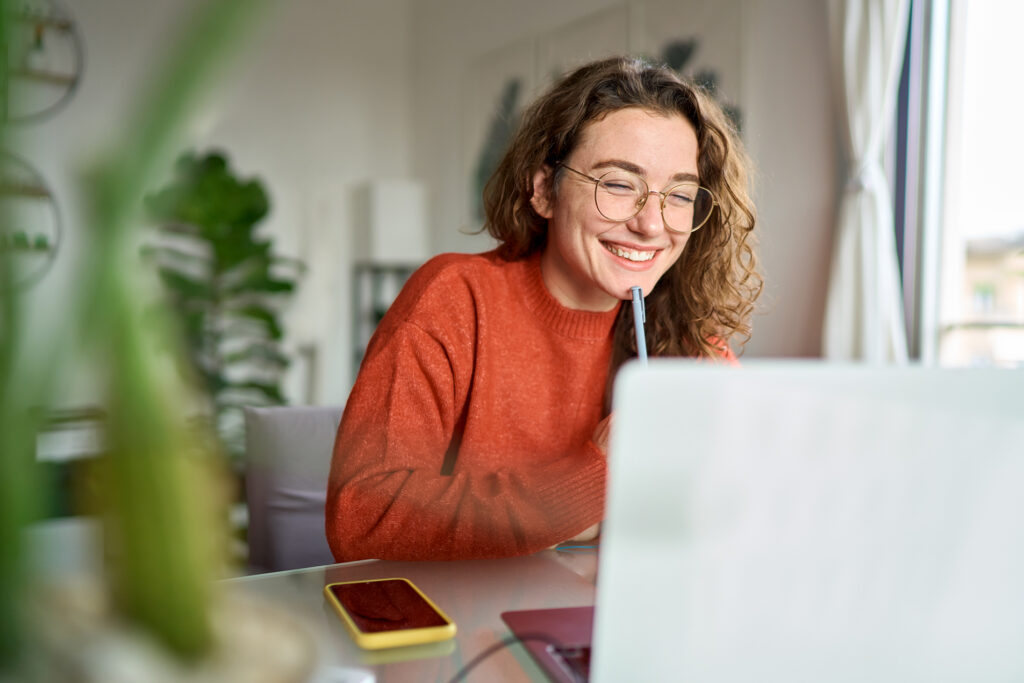 young happy female college student using laptop