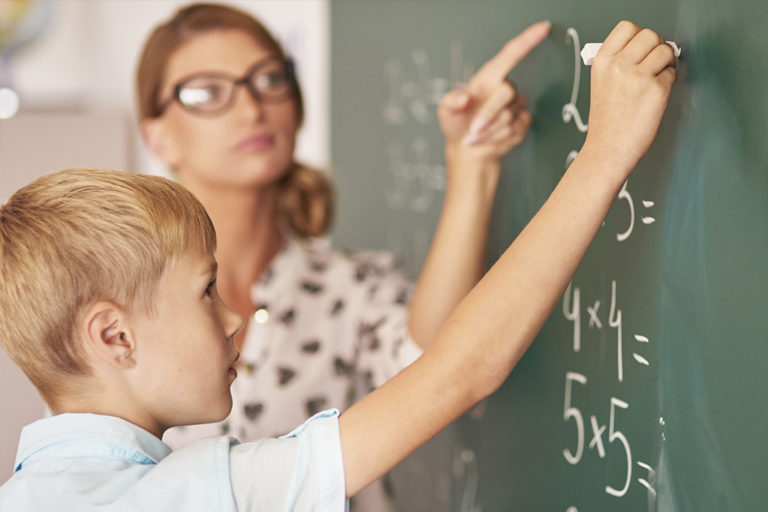 Teacher and student writing on chalkboard